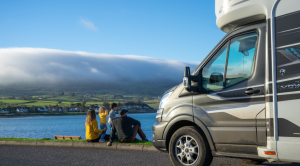 Family sitting outside motorhome parked by a lake